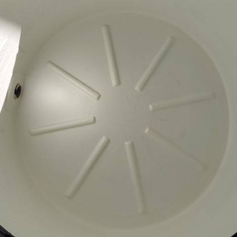 White circular ventilation grille or outlet with eight radial slots and a center screw on a ceiling or wall