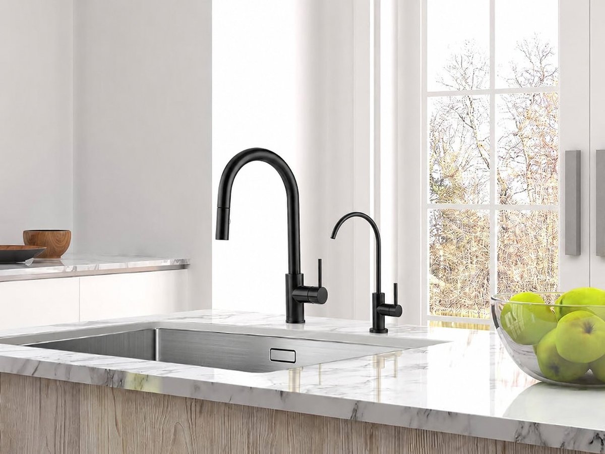 Modern kitchen sink with black pull-down faucet and white countertop, featuring green apples and window view